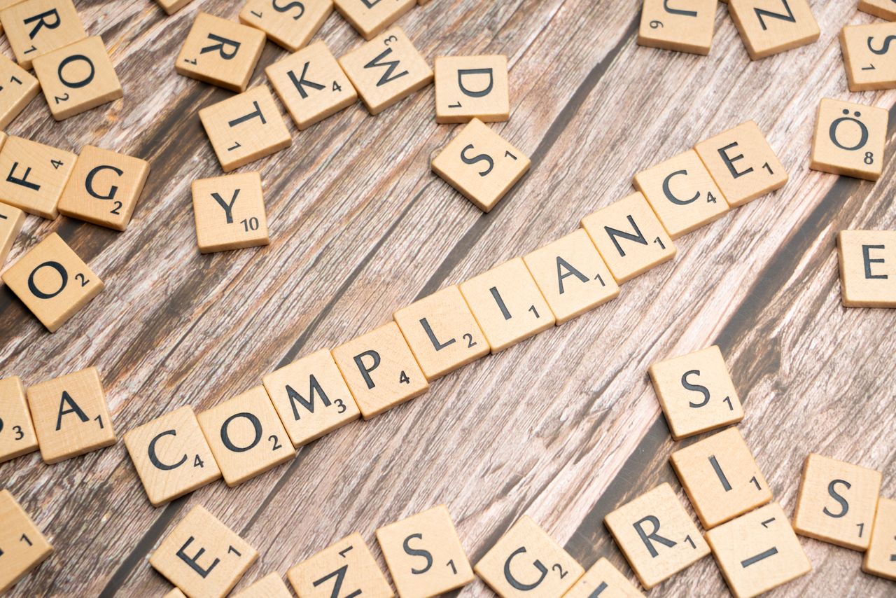 Wooden letter tiles spelling the word compliance.