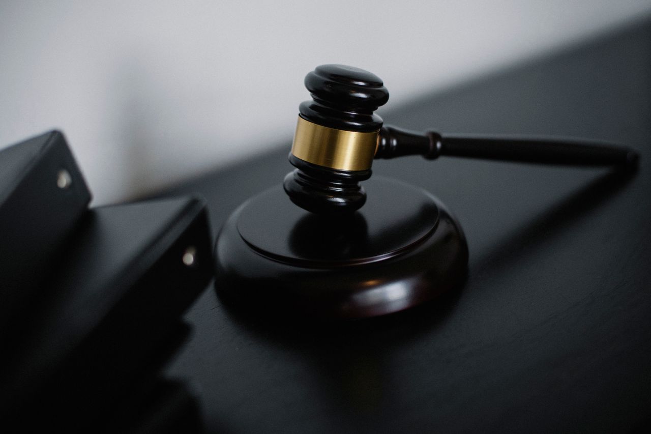 A wooden gavel on a dark desk beside a document folder.