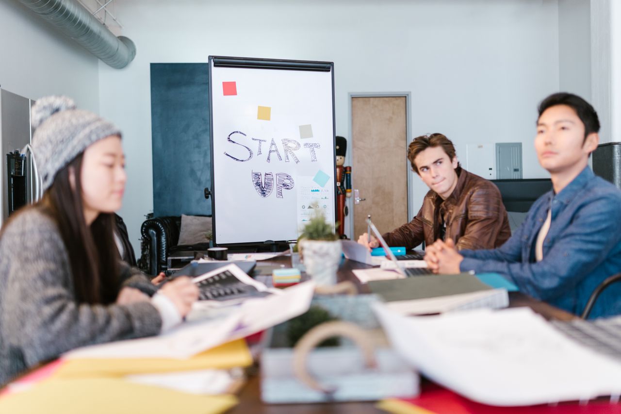 People seated at a table beside a 'Start Up' flip-chart.