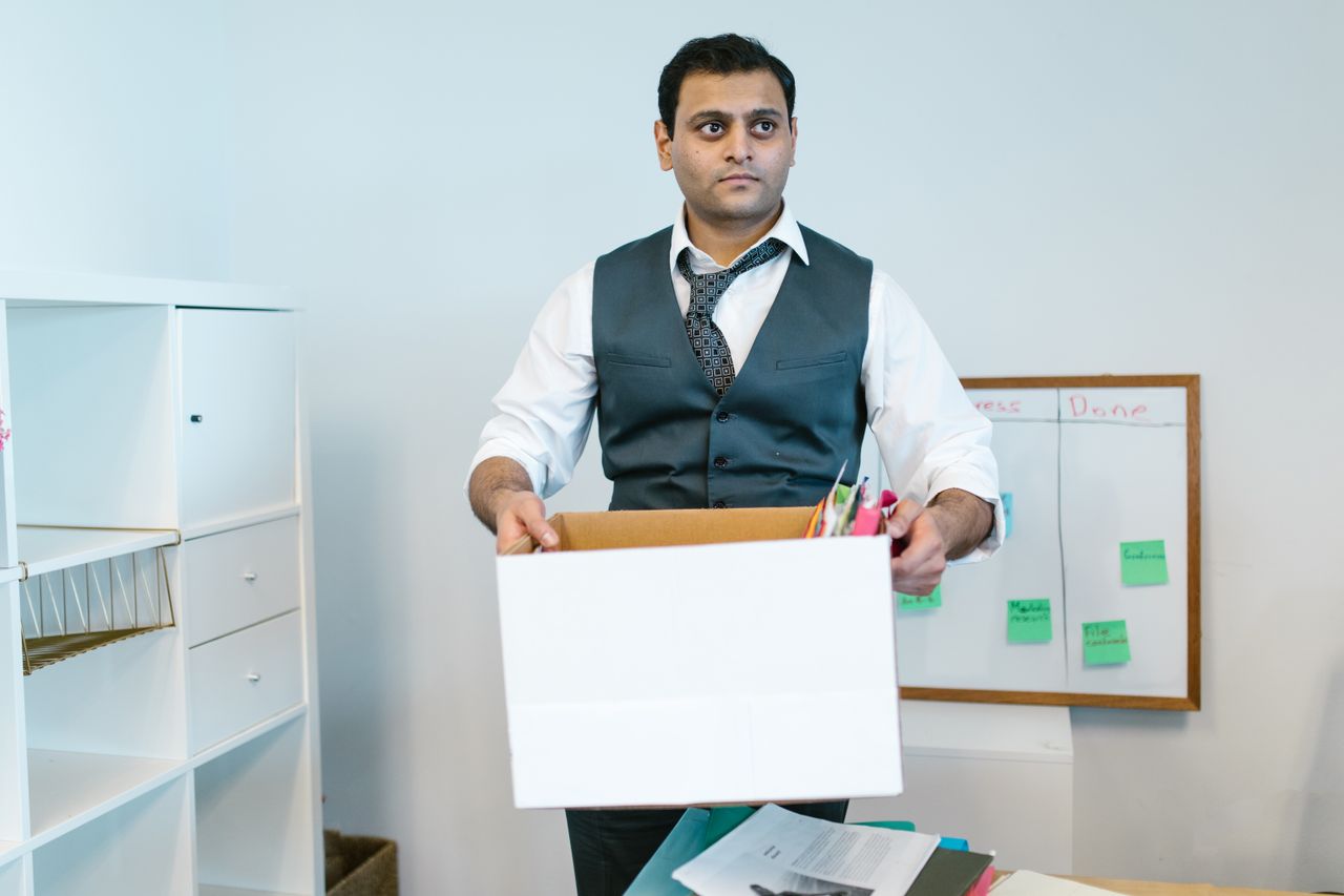Professional man organising office belongings in a cardboard box, preparing for transition.