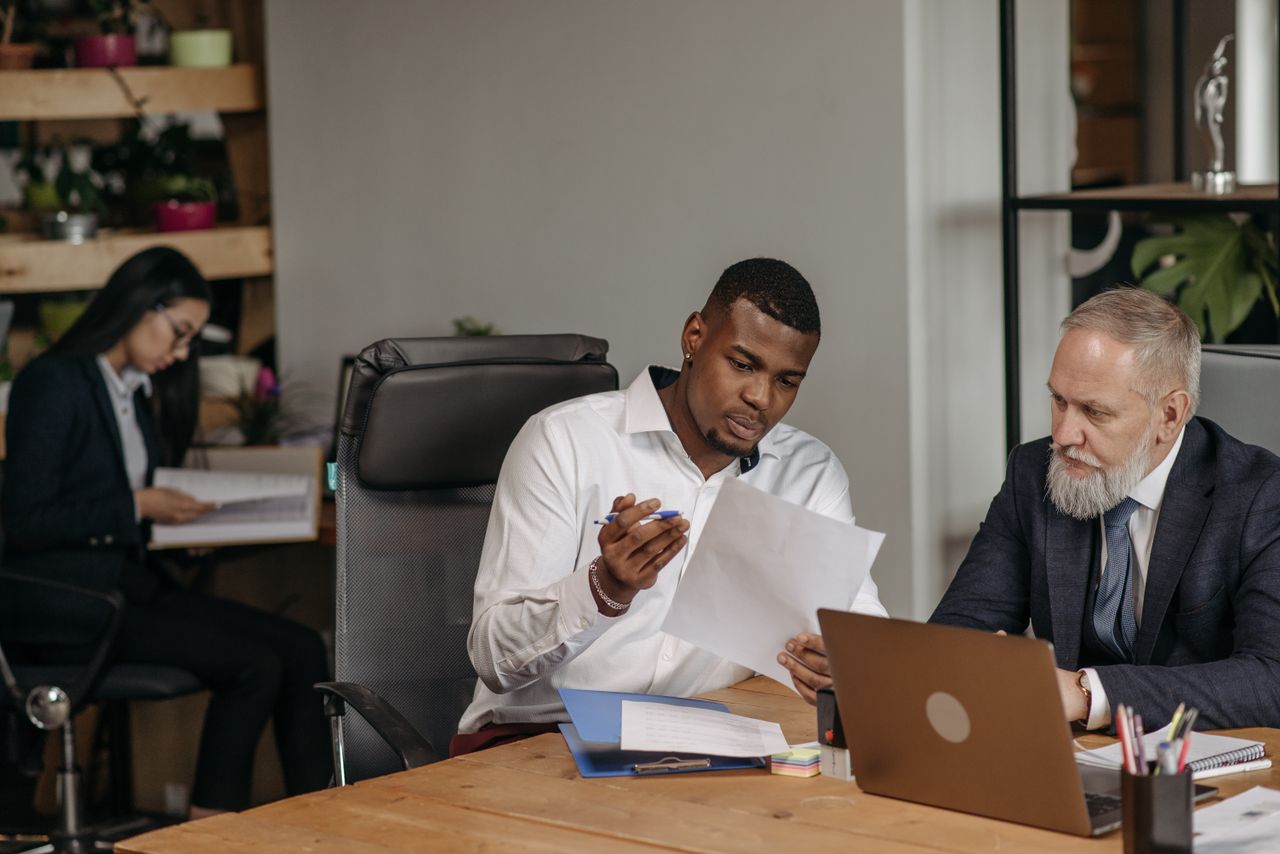 Business professionals discussing documents in a modern office environment with focus on teamwork and collaboration.