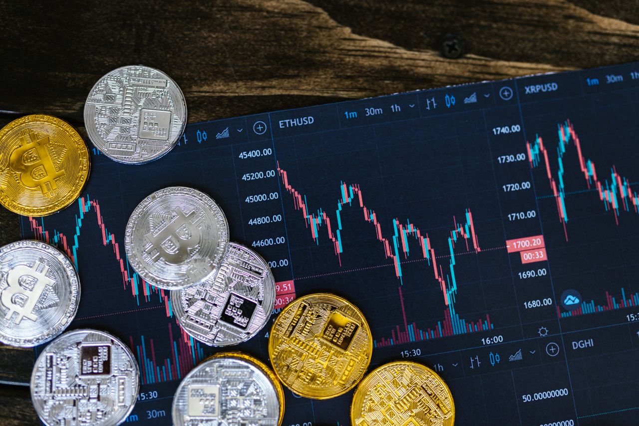 Physical crypto coins laid over a printed trading chart.